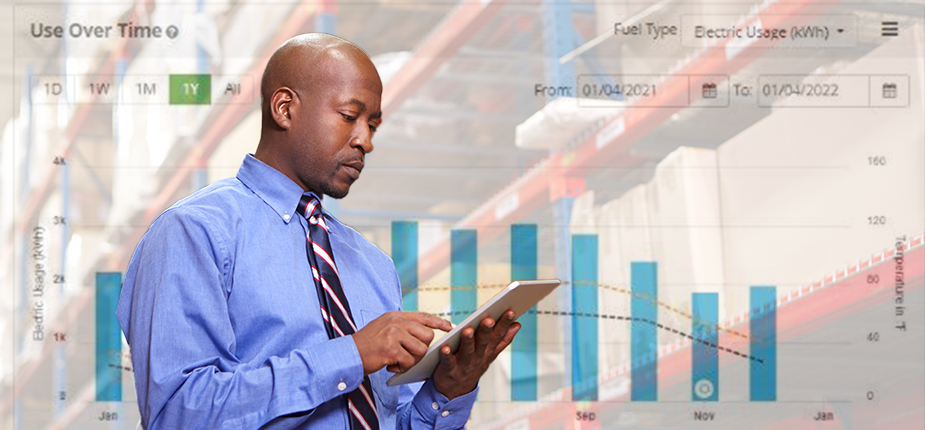 CFO in warehouse using a tablet to check their business’ electric use, with an image of the Consumers Energy energy use dashboard behind him.